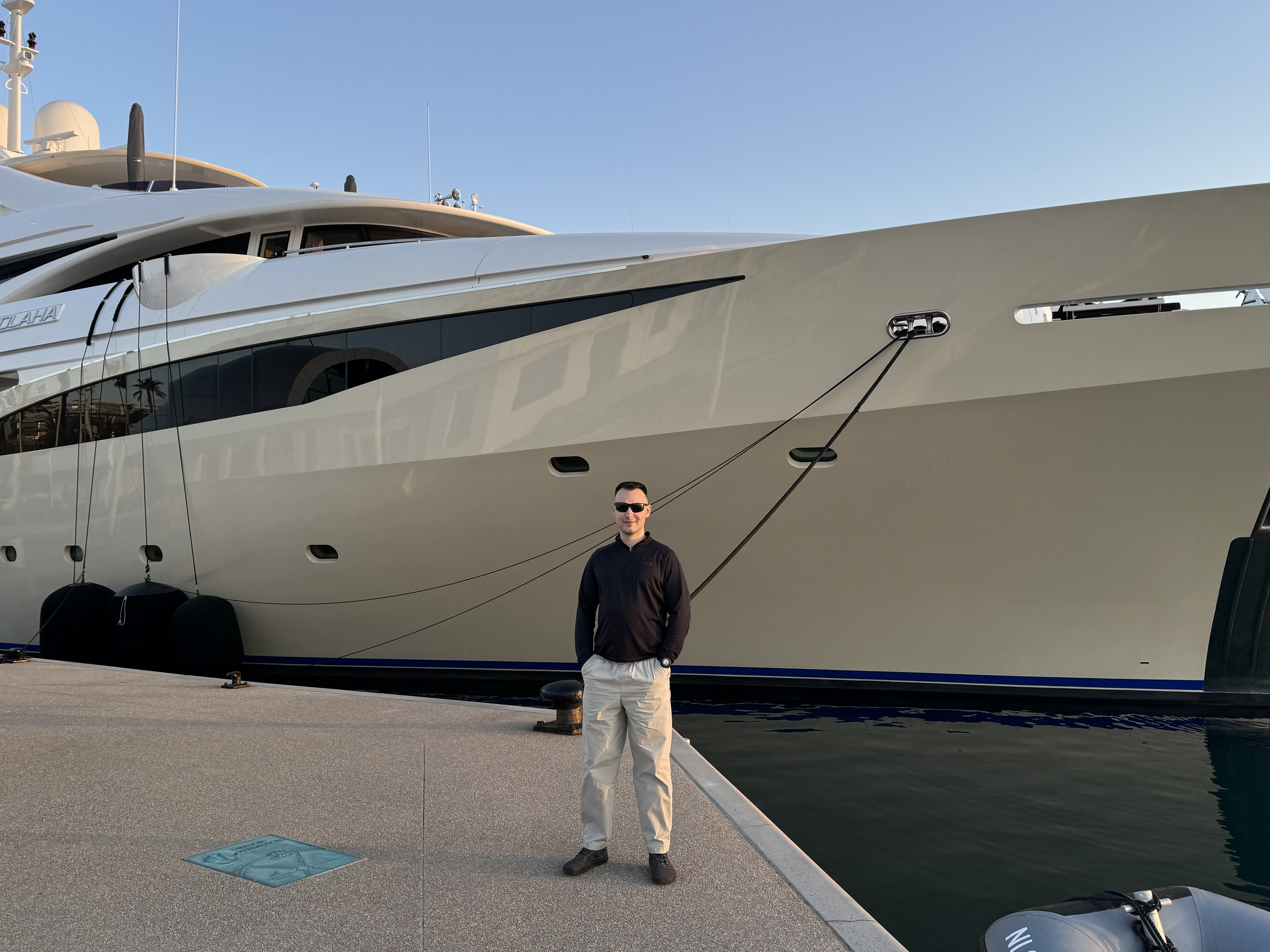 Rok standing on a dock in front of a yacht.