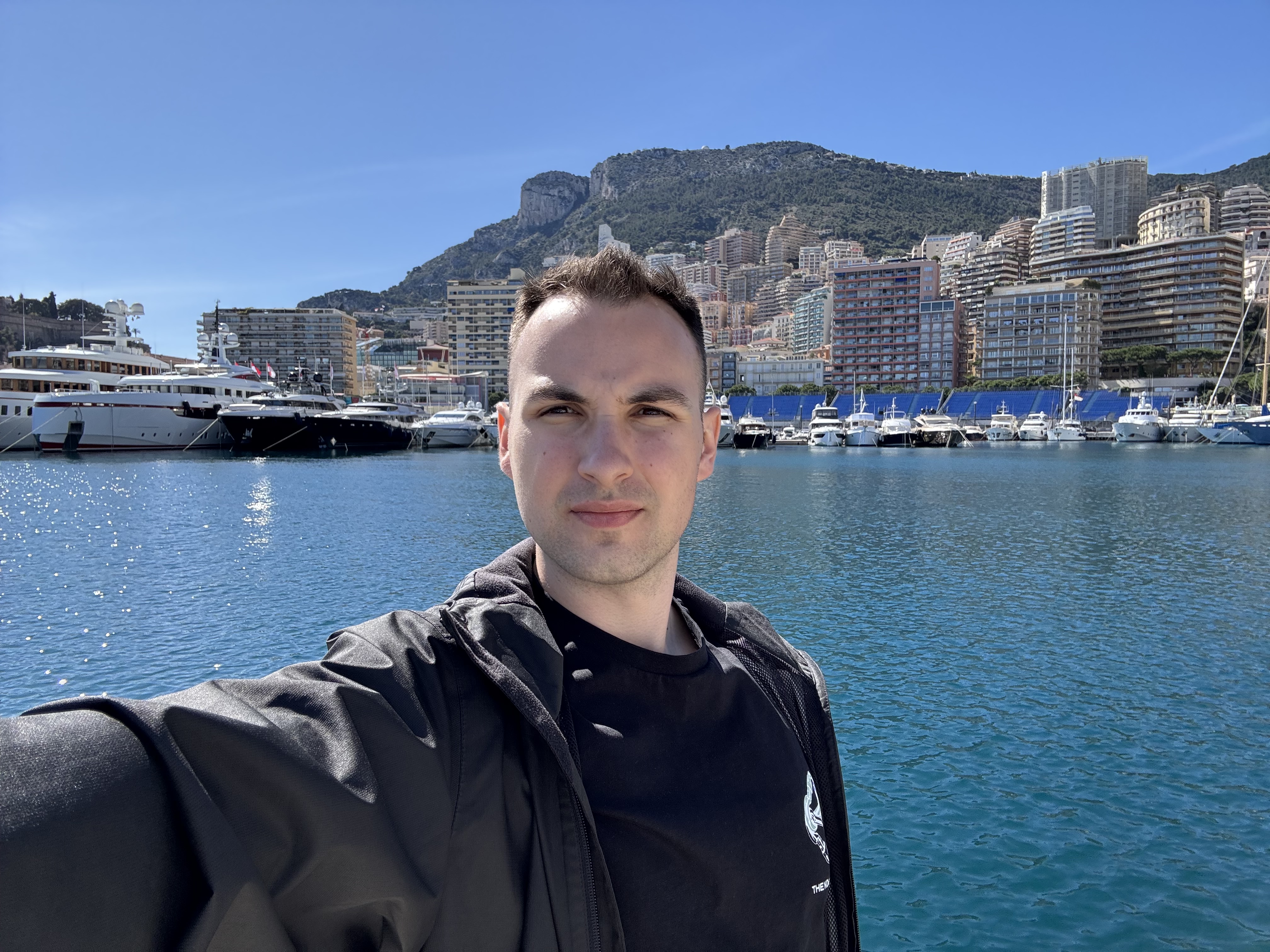Rok taking a selfie in front of a harbor and hillside city.