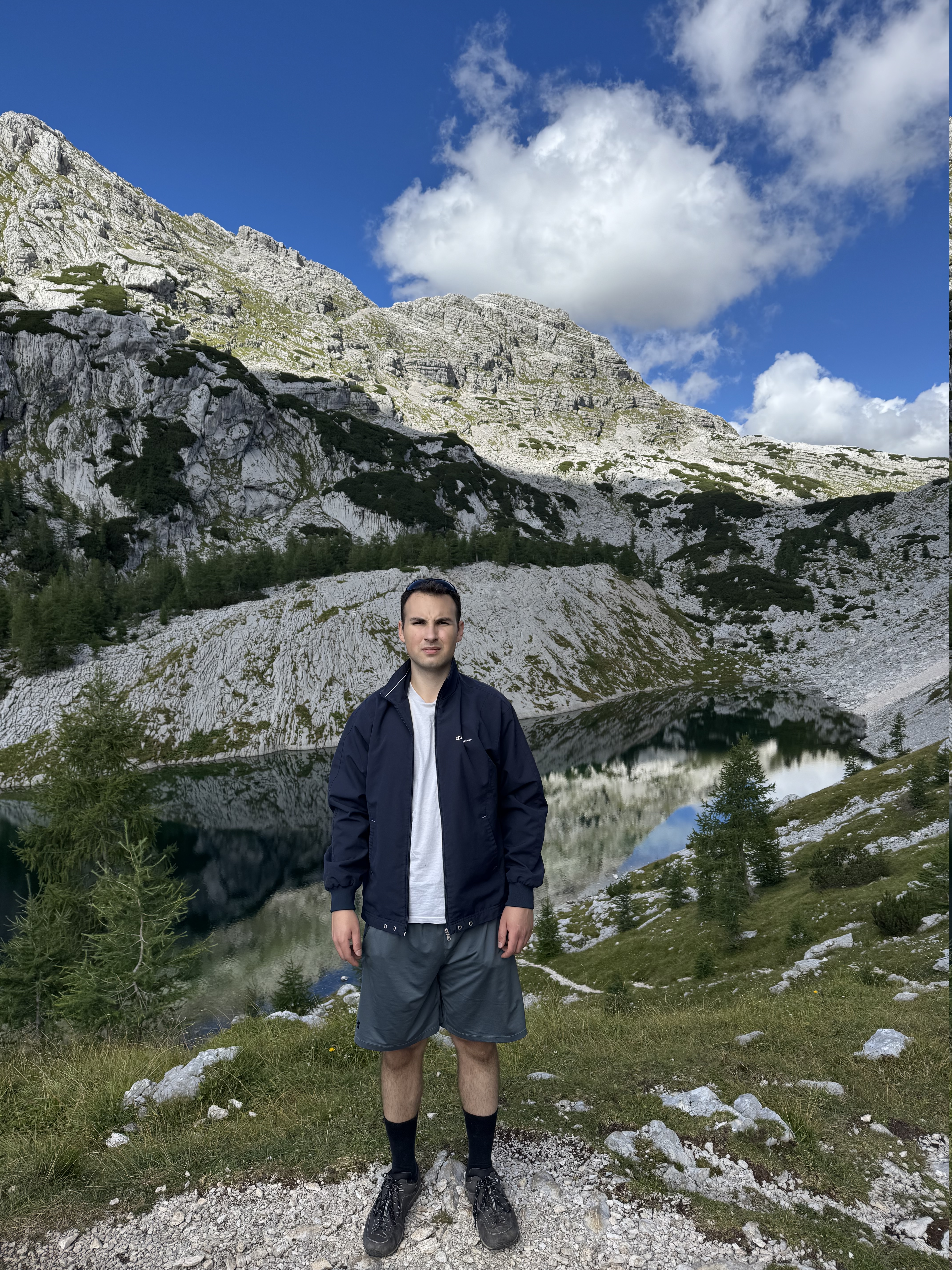 Rok standing below a rocky mountain and blue sky.