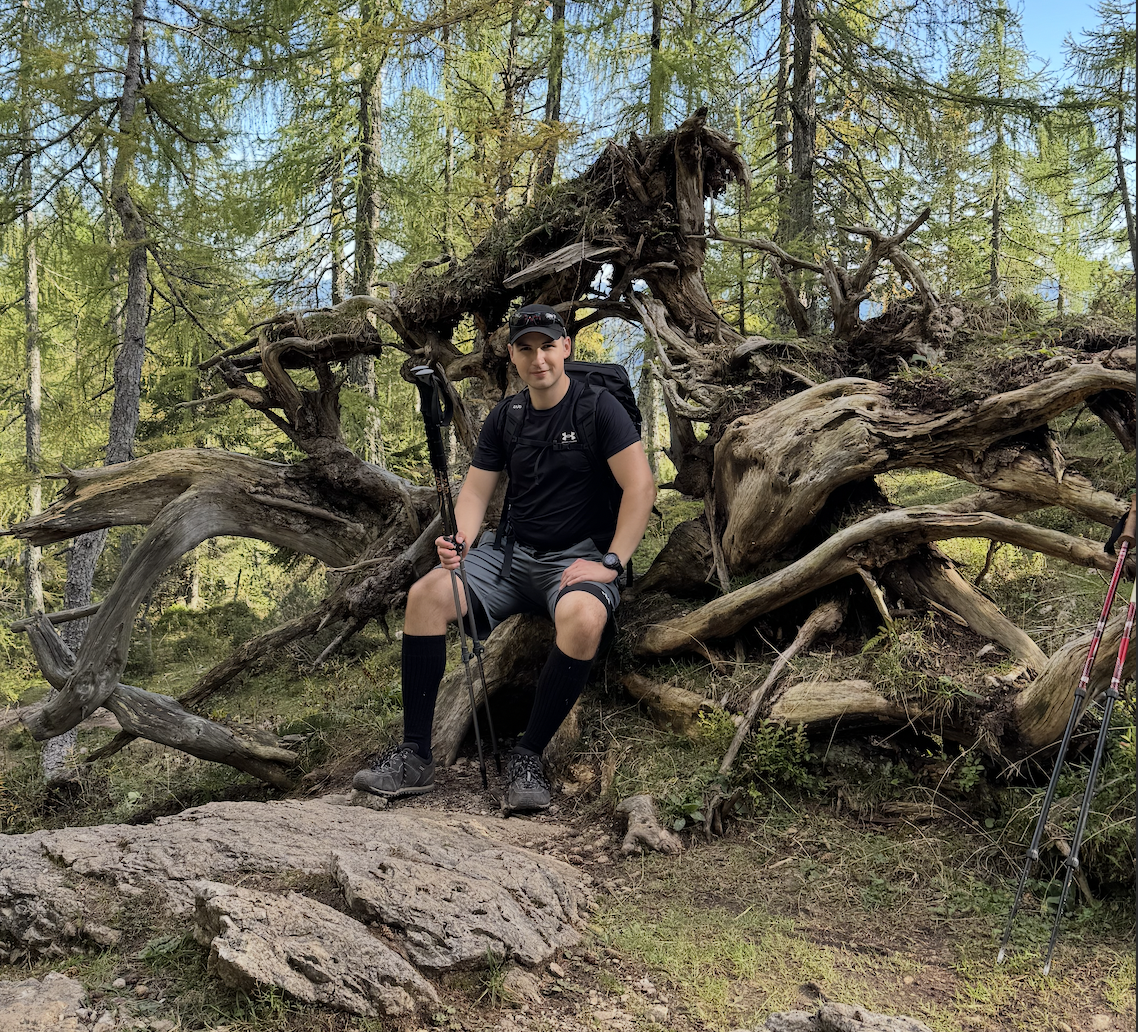 Rok sitting on a fallen tree while hiking.